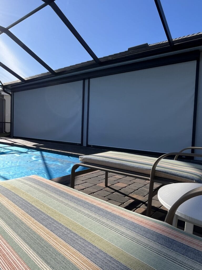 Motorized hurricane screen installed along a covered pool patio